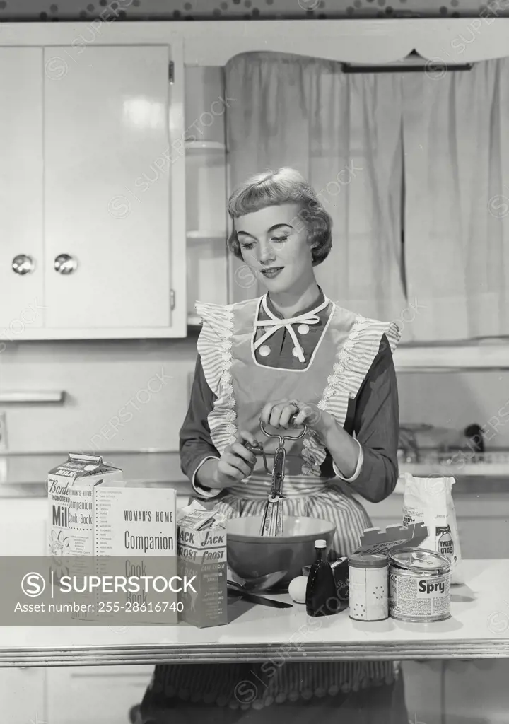 Vintage Photograph. Woman in apron mixing in bowl in kitchen. Frame 2