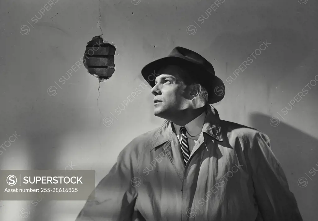 Vintage Photograph. Man in rain coat and hand standing up against wall. Frame 7