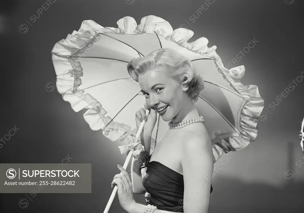 Vintage Photograph. Woman in dress holding umbrella over herself. Frame 2