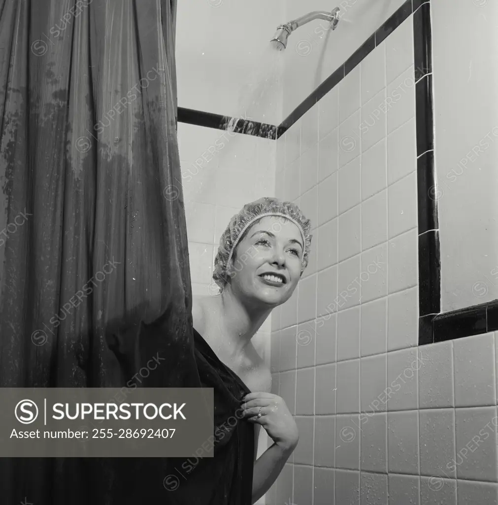 Vintage Photograph. Woman wearing shower cap peeking from behind shower  curtain with water running behind her - SuperStock