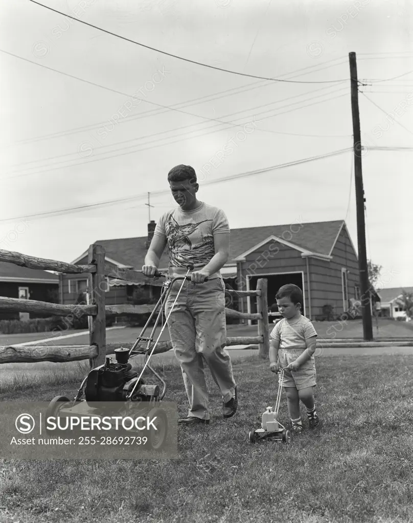 Vintage Photograph. Father mowing lawn with power mower as son walks alongside with toy mower Frame 2