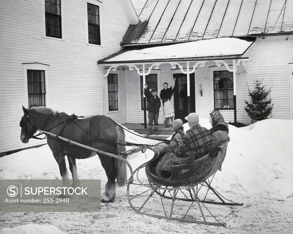 Grandparents waving at family sitting on sled