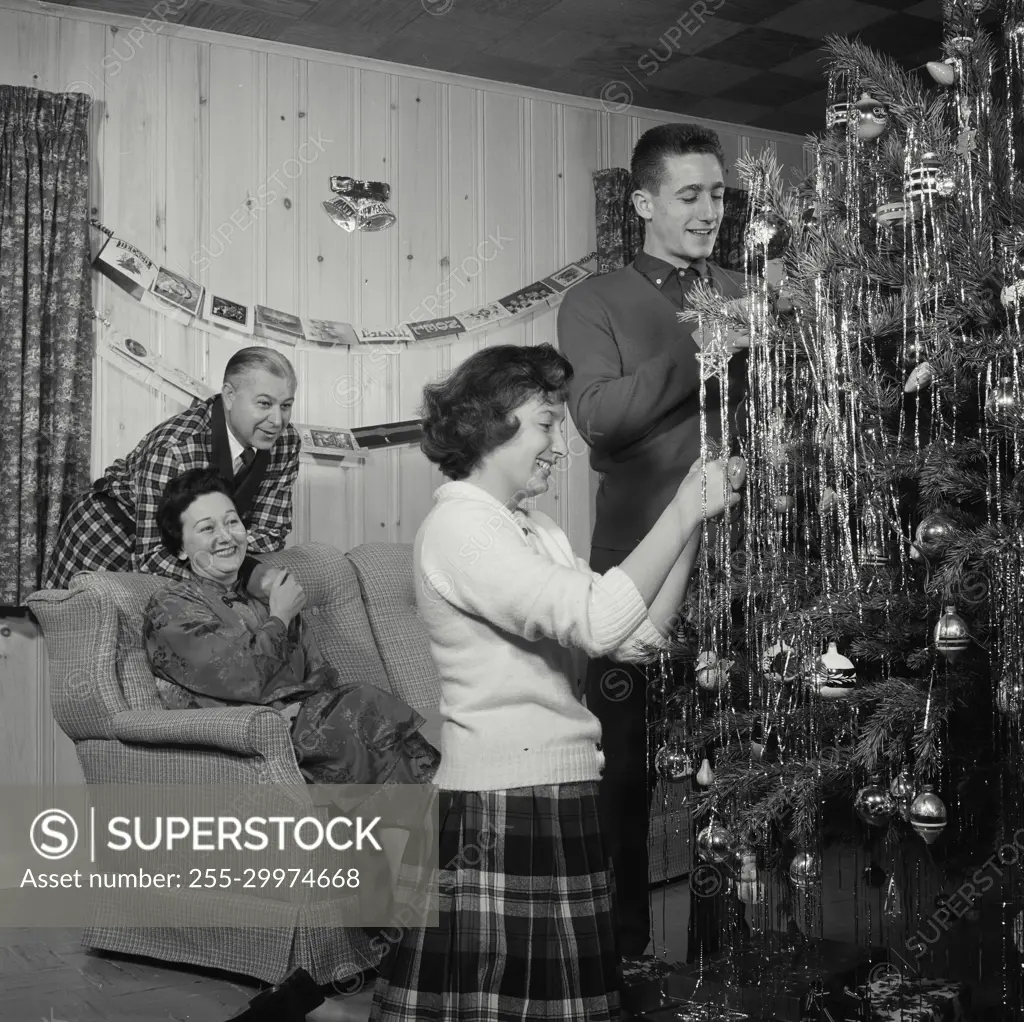 Vintage Photograph. Family Decorates Christmas tree together.