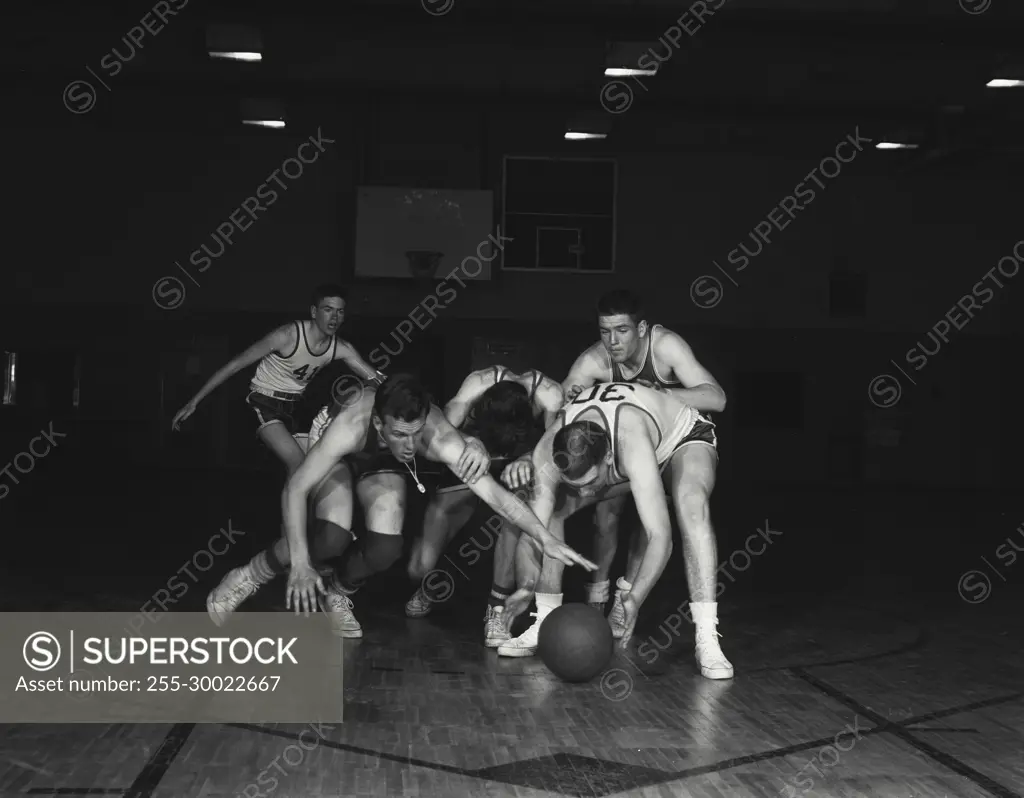 Vintage Photograph. Basketball players fight for ball on floor.