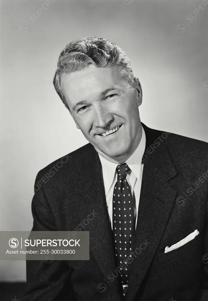 Vintage Photograph. Man smiles for studio portrait wearing business suit.