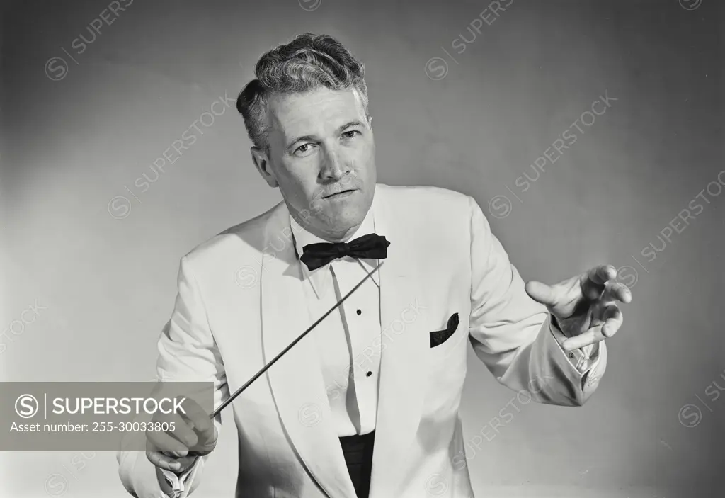 Vintage Photograph. Man directs band wearing white tuxedo.