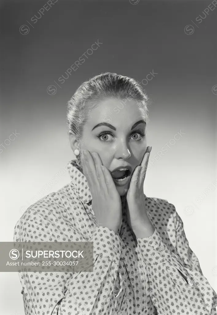 Vintage Photograph. Woman has a scared look on her face holding her cheeks with her hands.