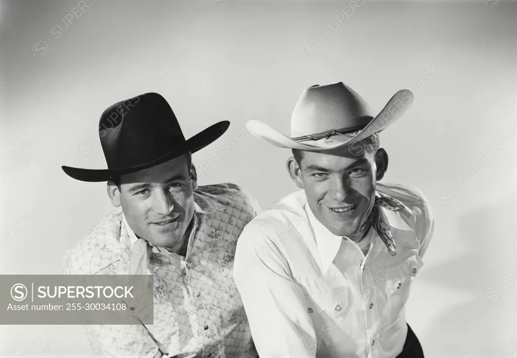 Vintage Photograph. Men sit next to each other in studio portrait wearing cowboy hats.