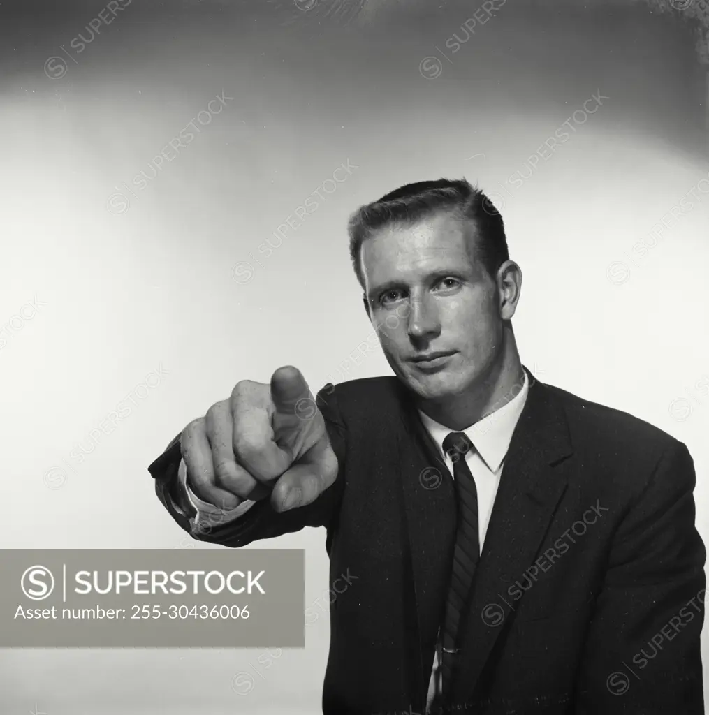 Vintage Photograph. Man points at camera in studio portrait.