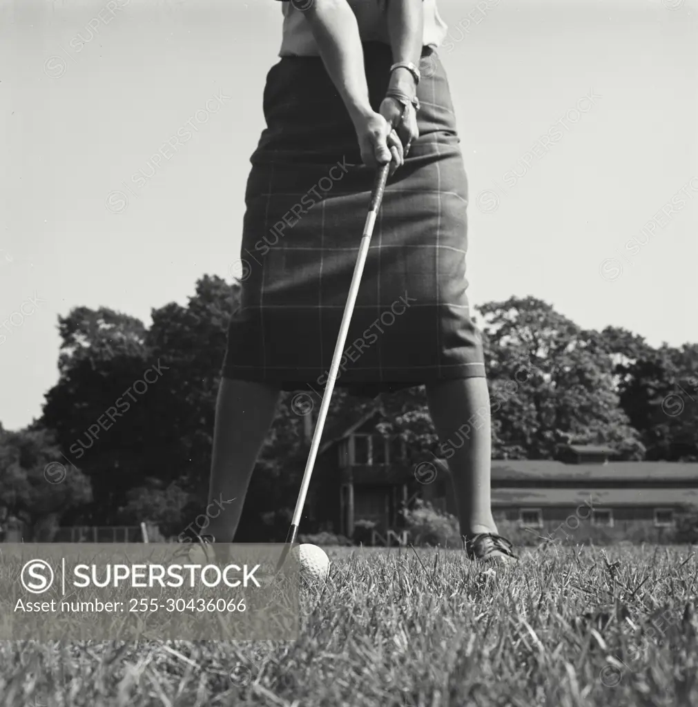 Vintage Photograph. Closeup of woman lining up her swing to hit golf ball.