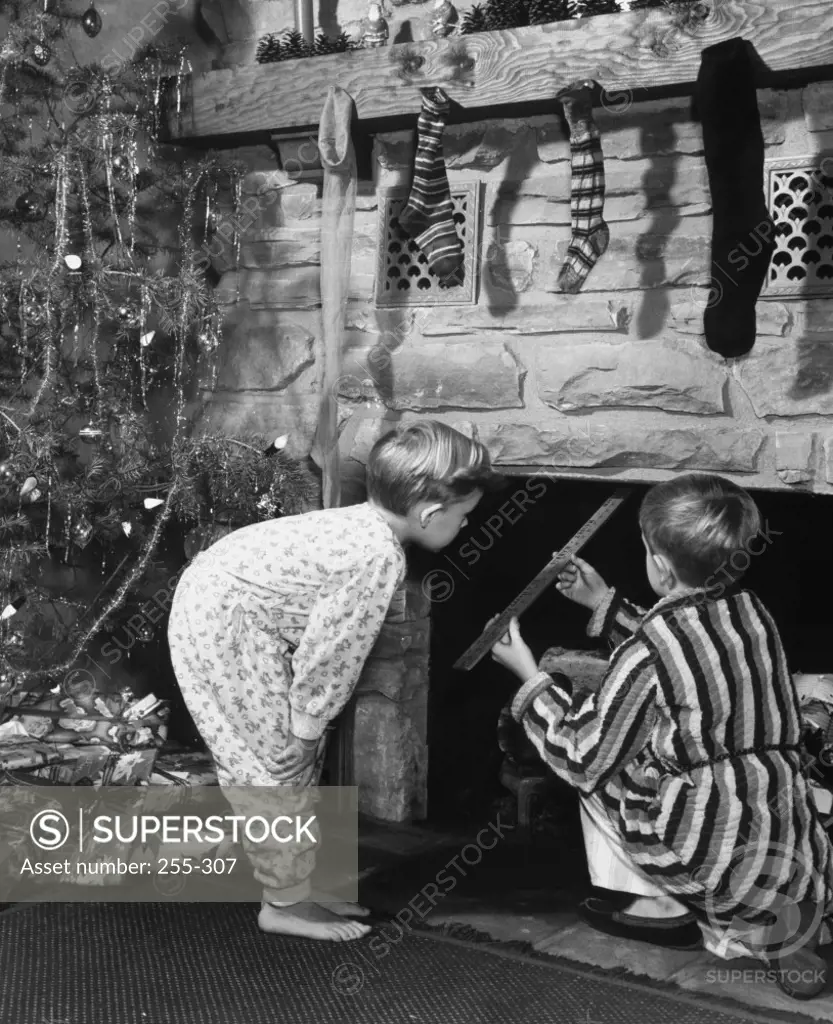 Two boys peeping into a fireplace