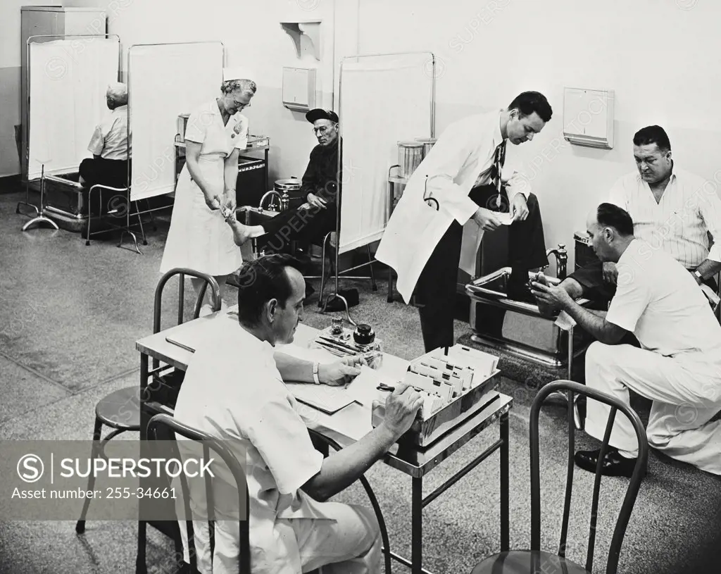 Vintage photograph. Doctors and a female nurse with patients in a hospital