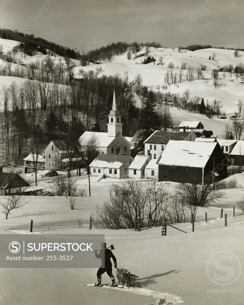 High angle view of a man pulling a Christmas tree on a snow covered landscape