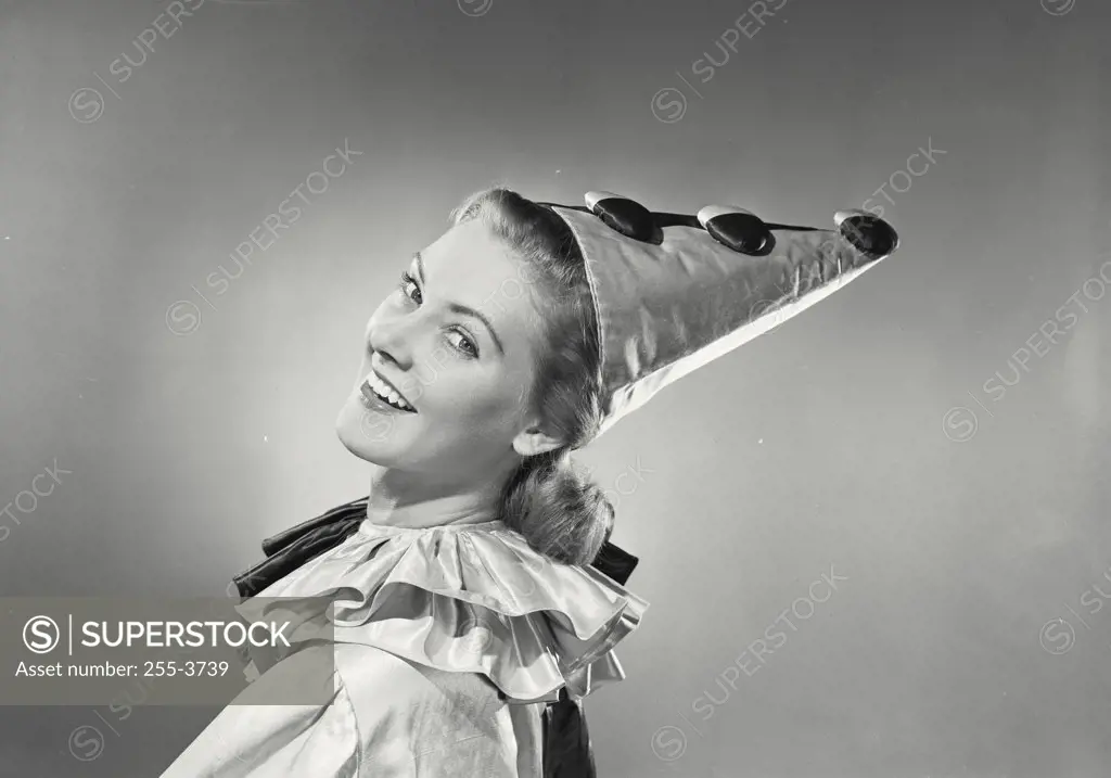 Vintage photograph. Portrait of a young woman in clown suit looking over shoulder and smiling.