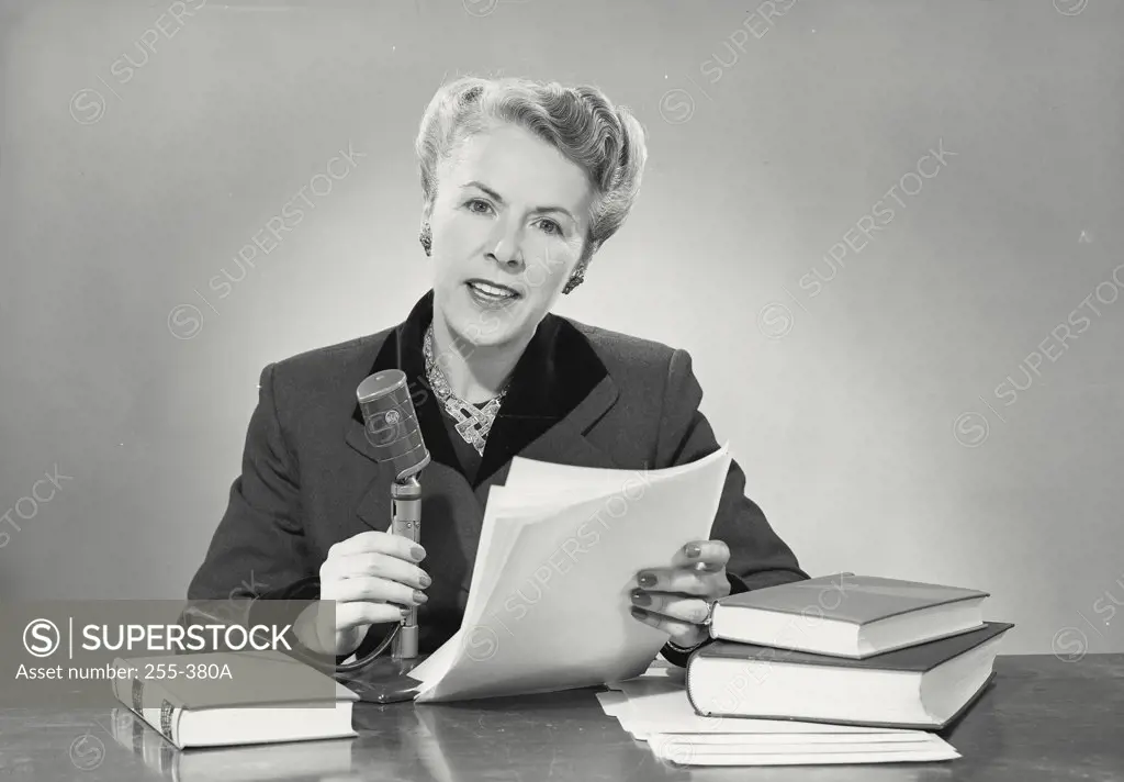 Vintage photograph. Portrait of a mid adult woman news anchor with microphone and stack of papers