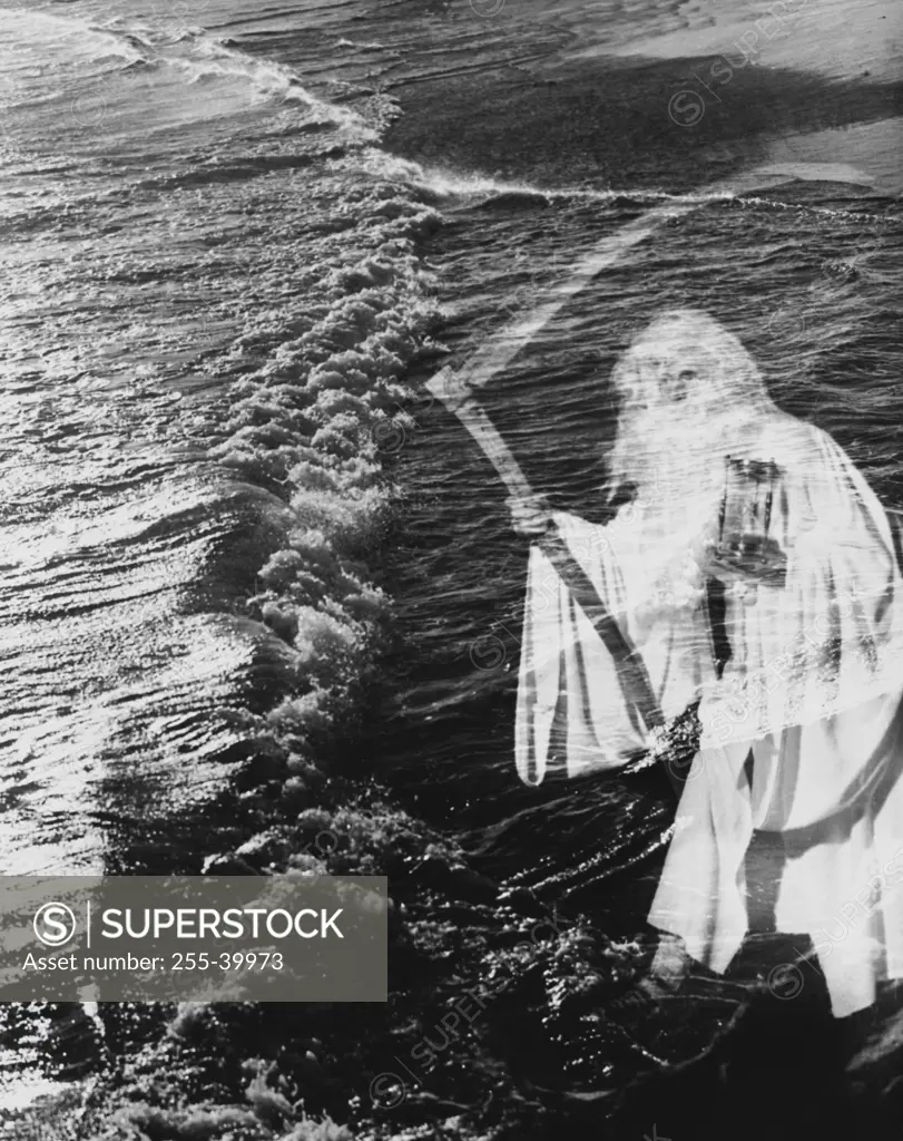 Senior man holding scythe and hourglass on the beach