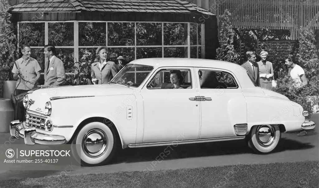 Group of people standing behind a car, 1949 Studebaker Land Cruiser