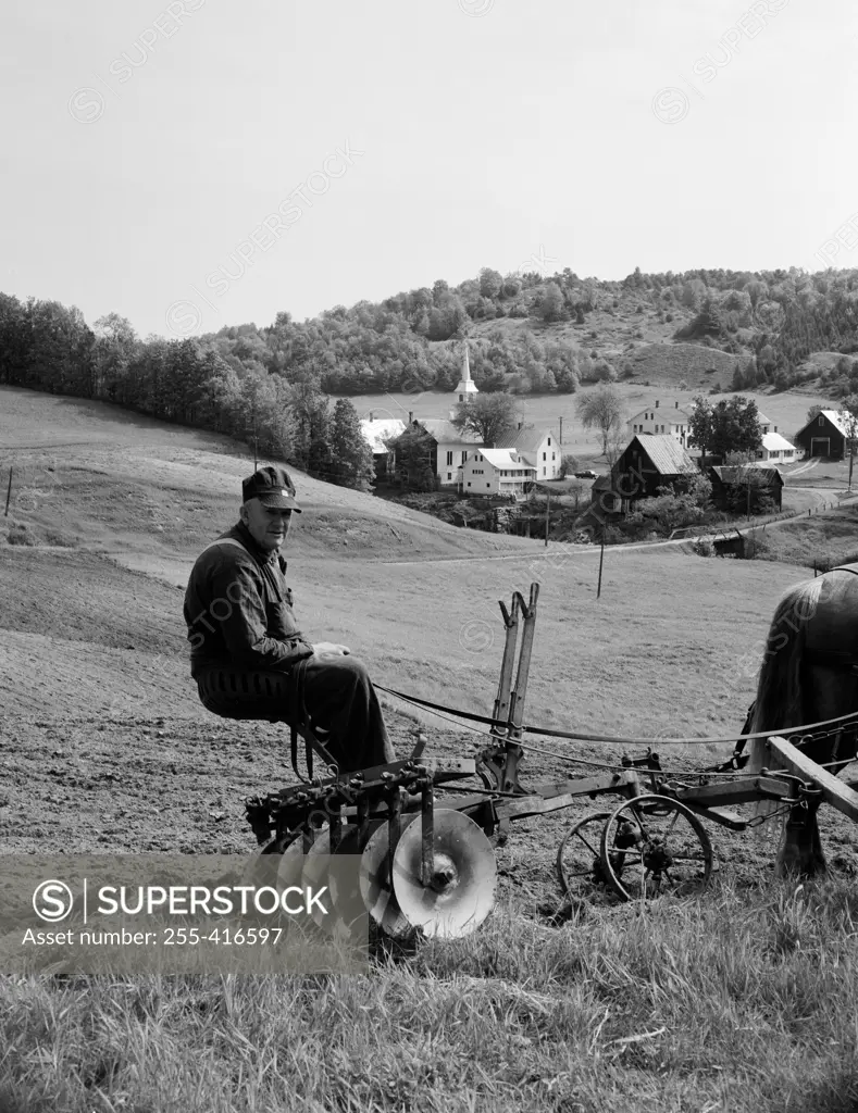 USA, Vermont, Corinth, farmer sitting on agriculture machine pulling by horse