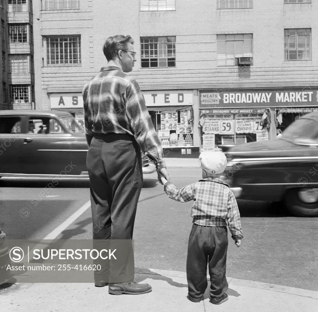 Father with son waiting at pavement to cross road