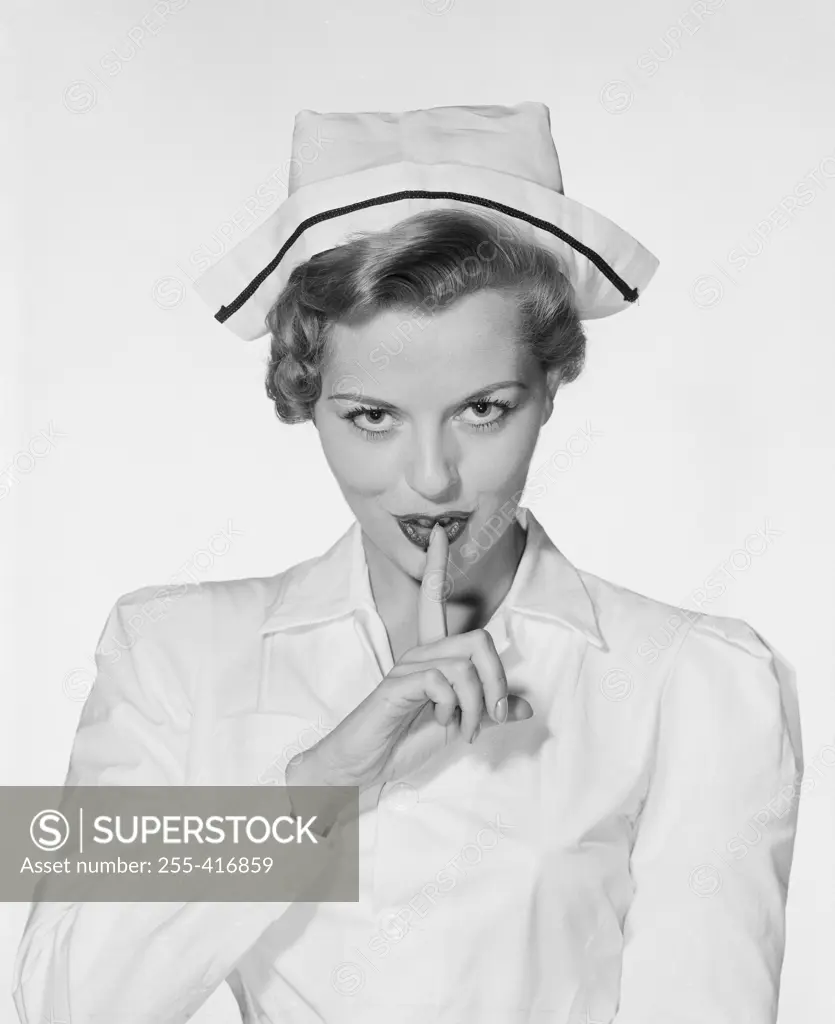 Studio portrait of female nurse gesturing silence