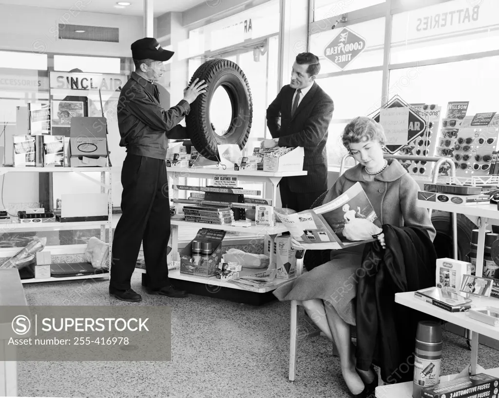 Man buying tire and woman reading magazine