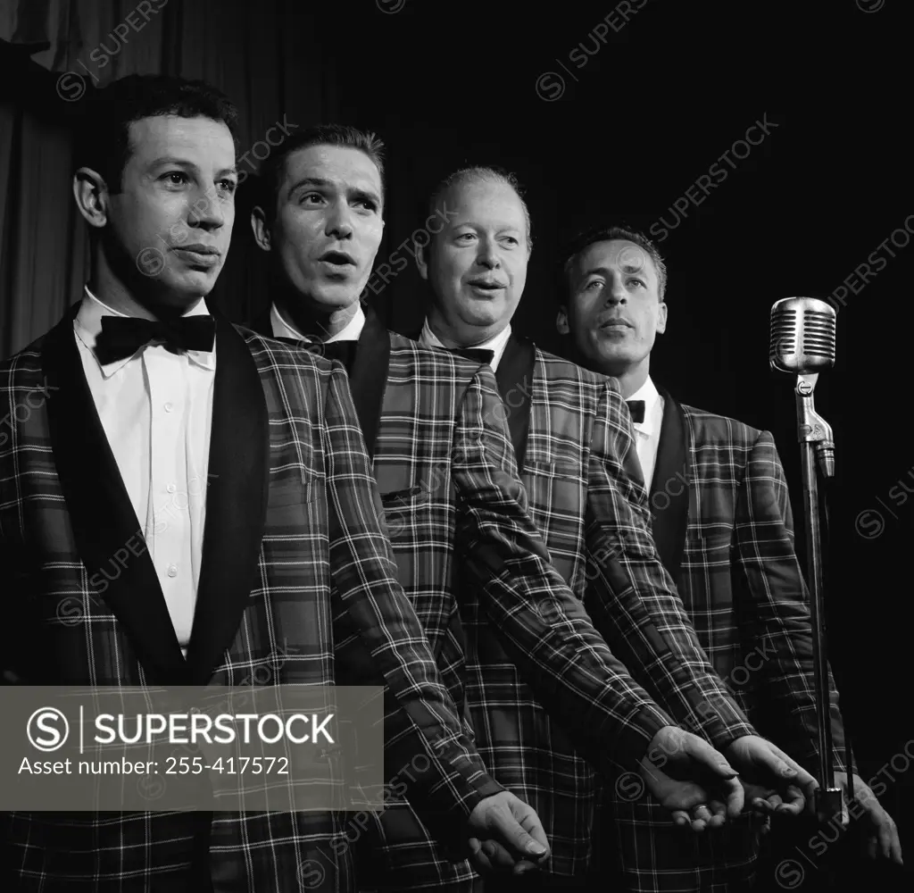 Four male singers performing on stage