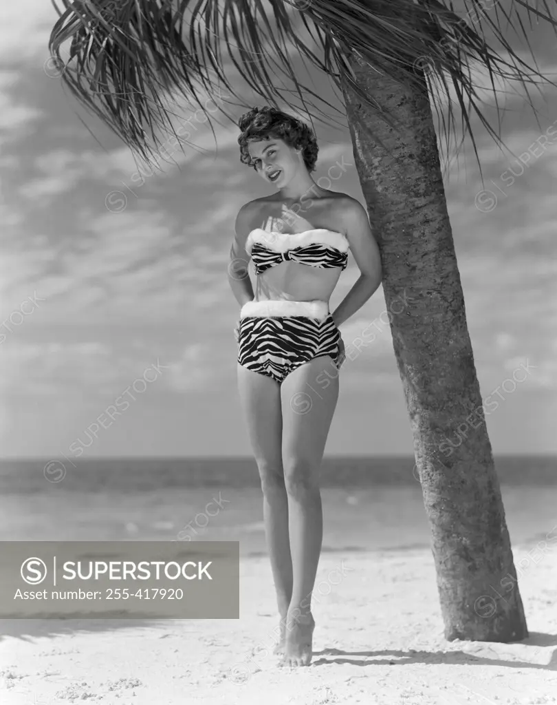 Pin-up girl standing under palm tree, wearing bikini