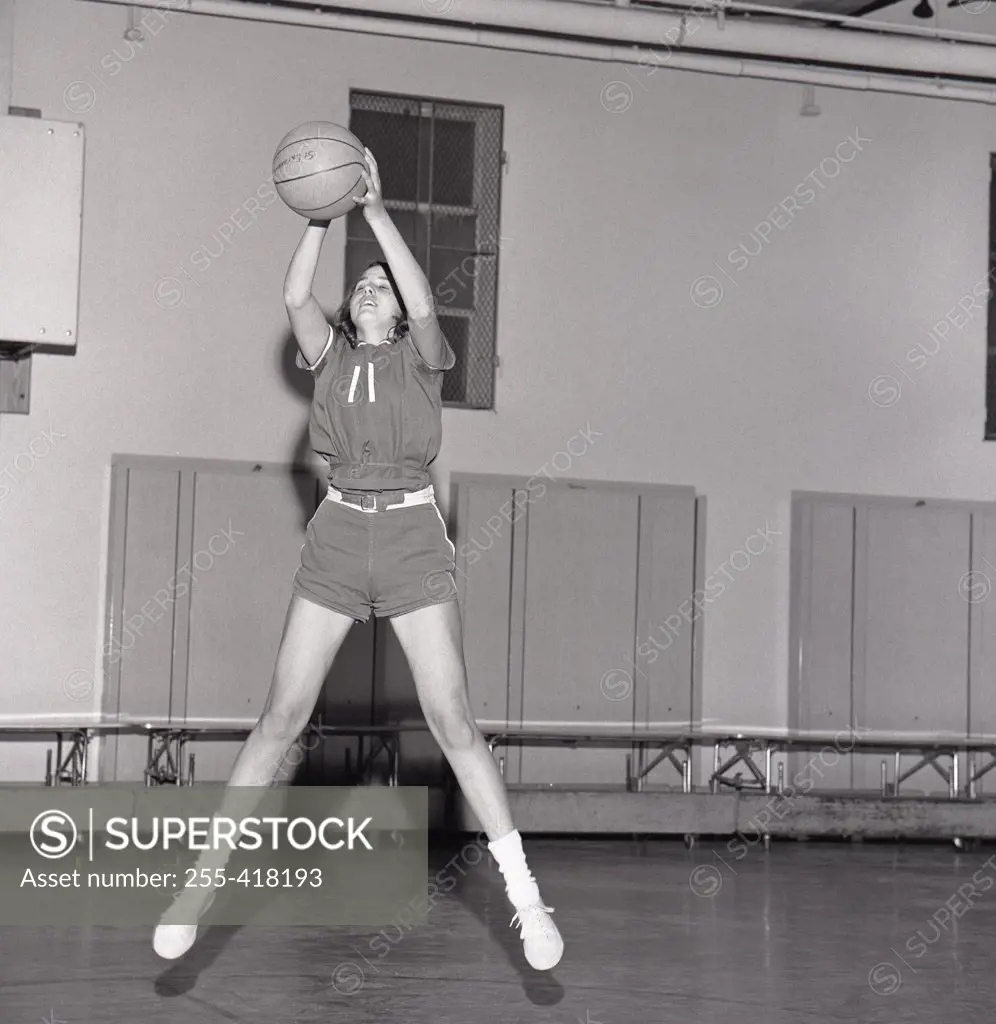 Girl jumping with basketball ball