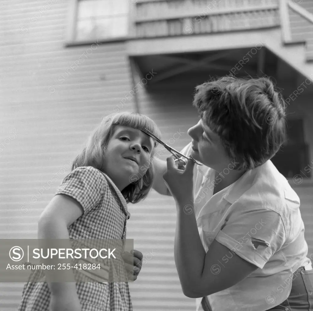 Mother cutting daughter's fringe