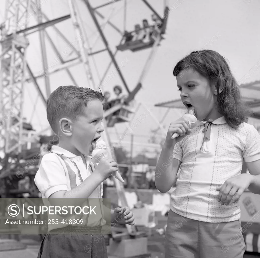 Two kids eating ice-creams in amusement park