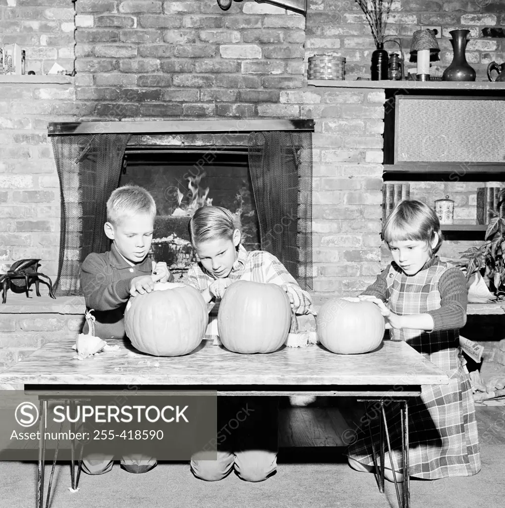 Girl and two boys preparing Jack O' Lantern for Halloween