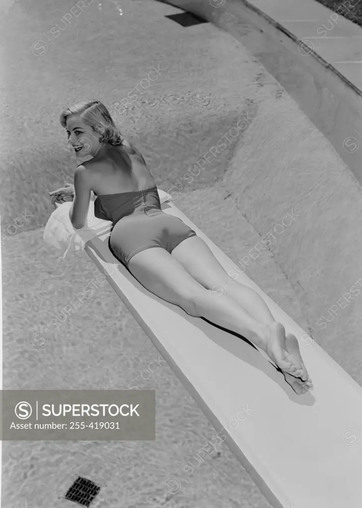 Young woman in swimwear lying on diving board