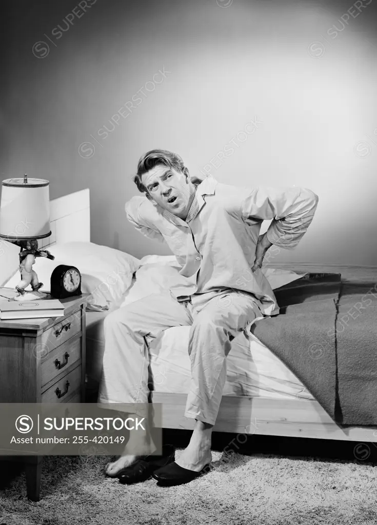 Mid adult man wearing pajamas sitting on bed