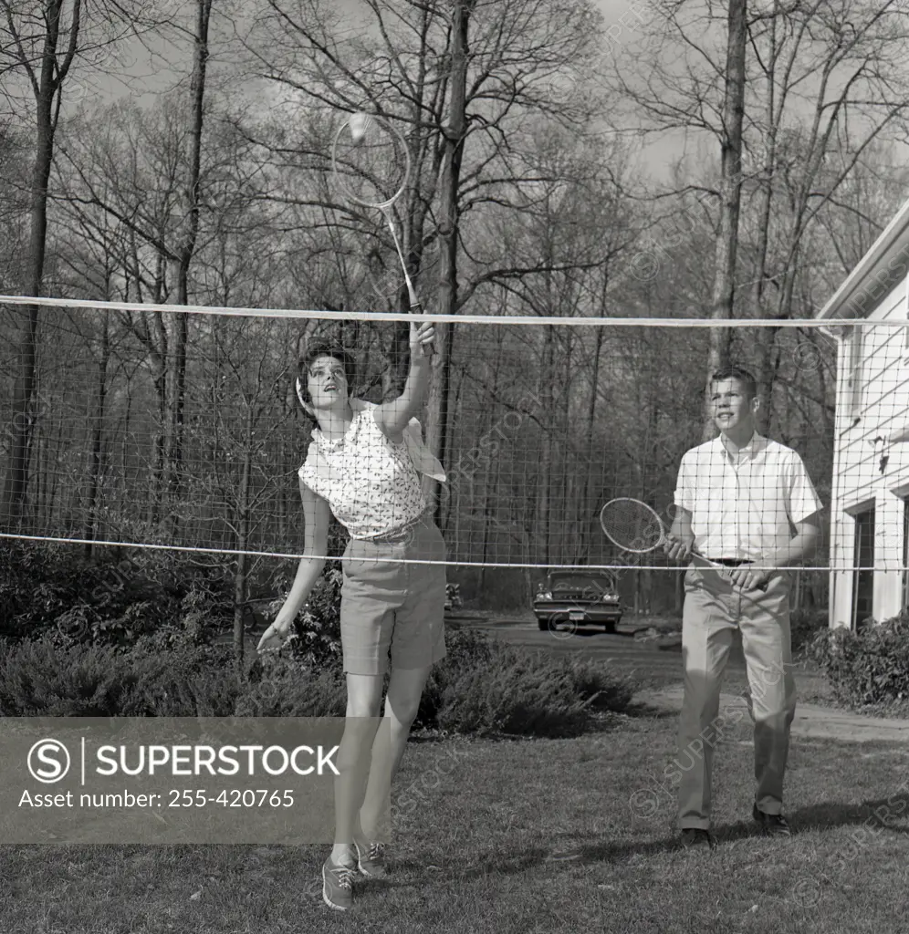 Young woman and young man playing badminton