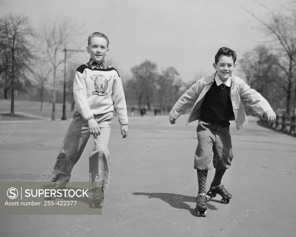 Two boys roller skating in park