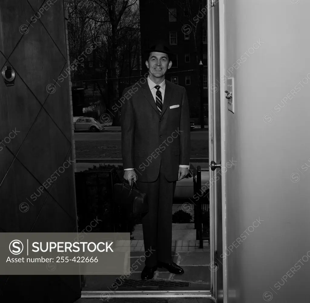 Man wearing suit standing in doorway of house