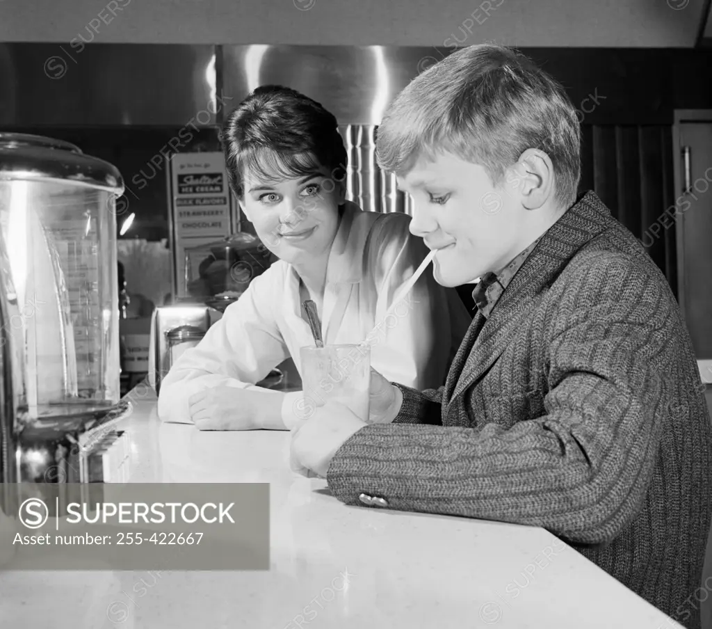 Woman looking at boy drinking milk shake