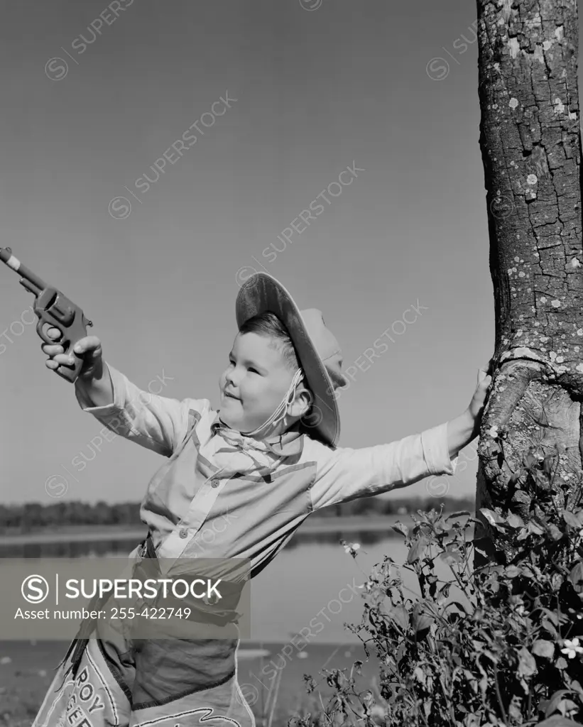 Boy dressed as cowboy playing with toy gun