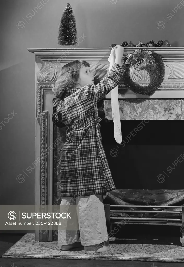 Girl hanging Christmas stocking on mantelpiece