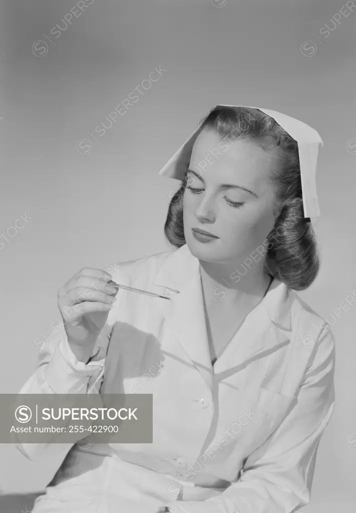 Young nurse looking at thermometer