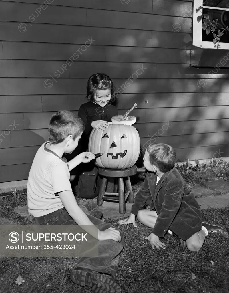 Boys and girl preparing pumpkin for Halloween party