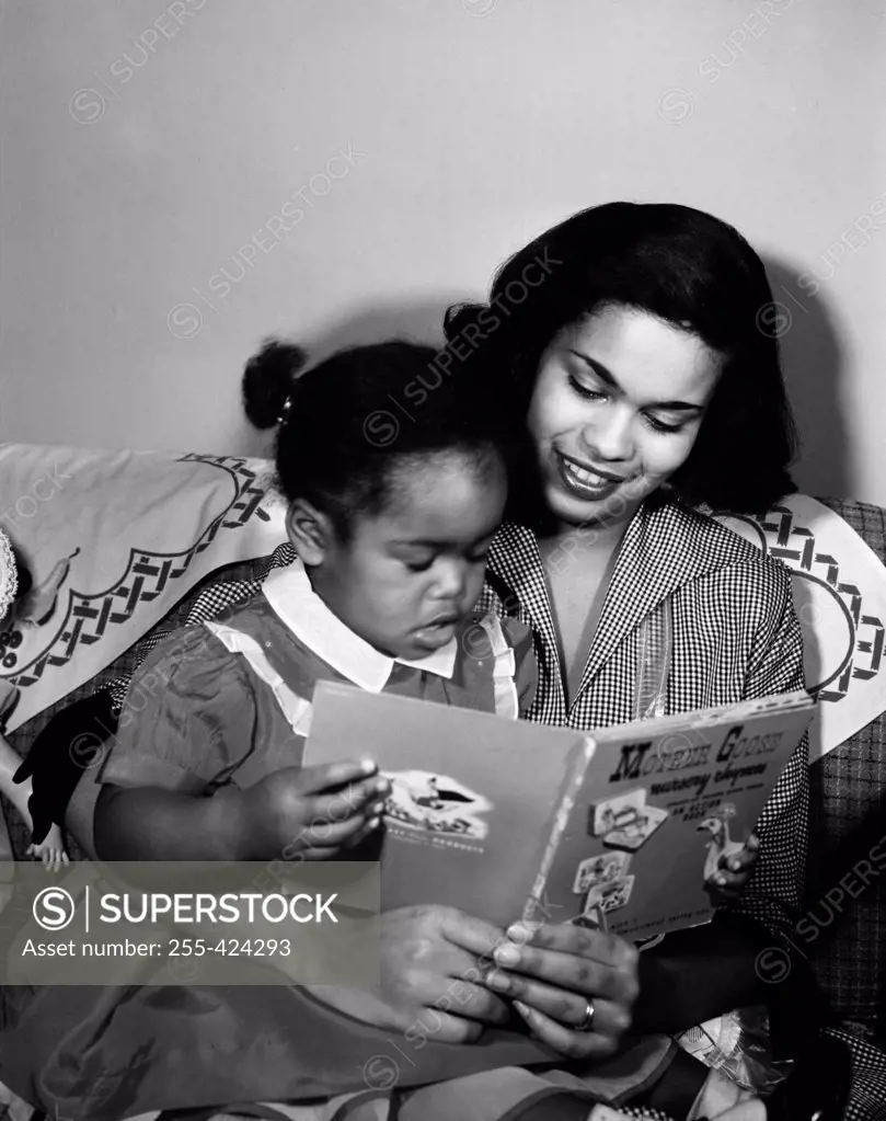 Mother reading book to young daughter