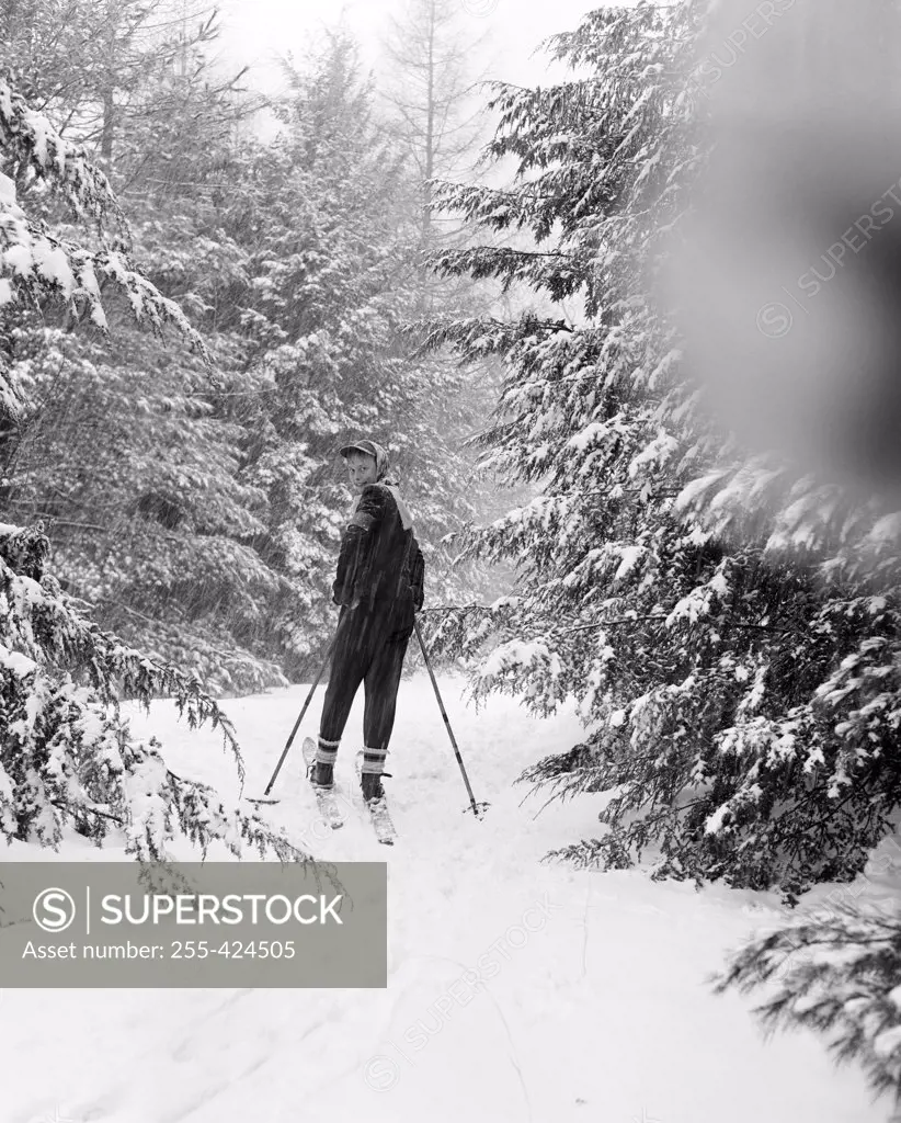 Teenage boy skiing in forest