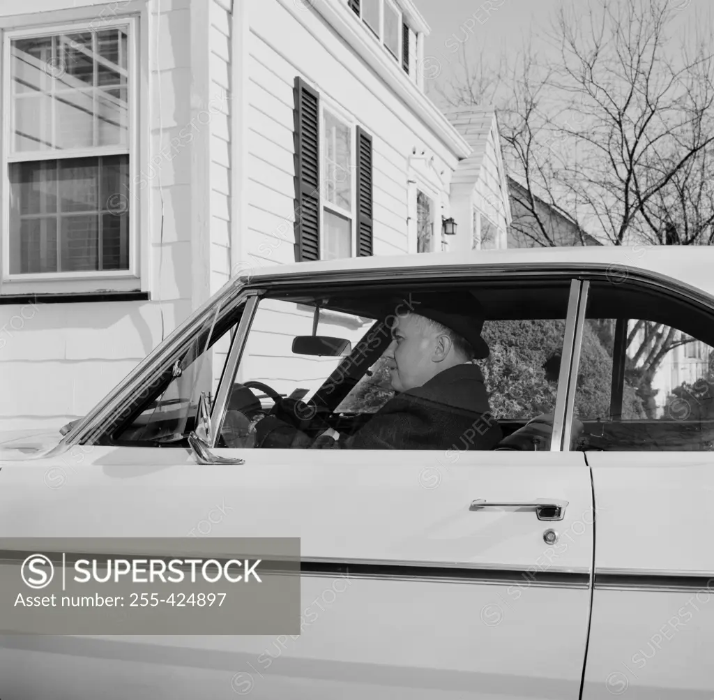 Man sitting in car outside house