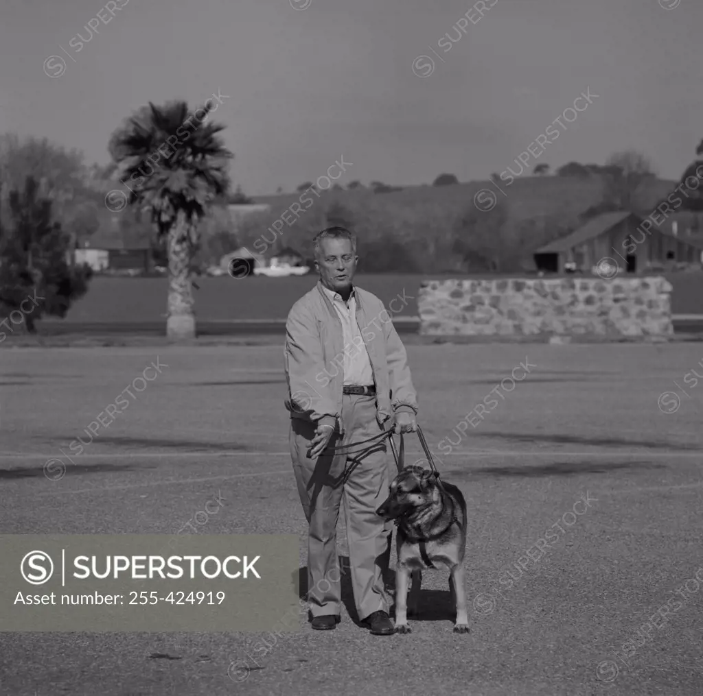 Blind man walking with guide dog in park