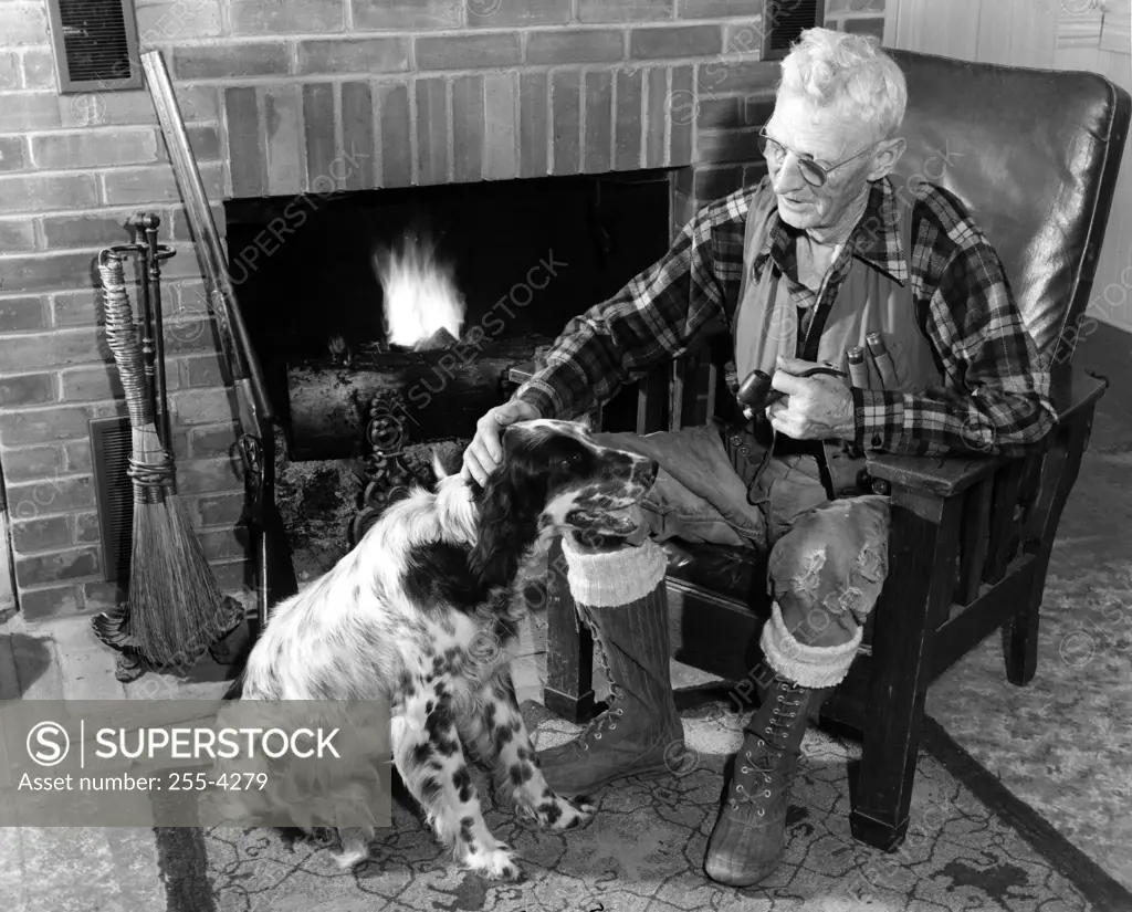 Senior man sitting next to fireplace stroking dog