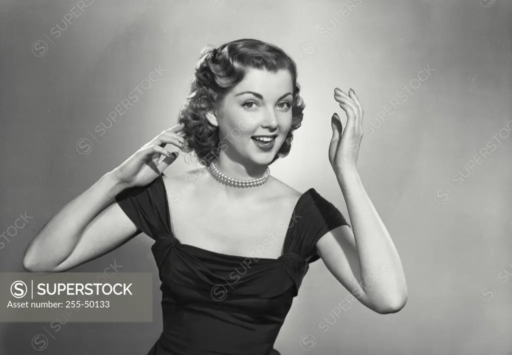 Vintage Photograph. Woman in low cut gown and pearls smiling with hands up