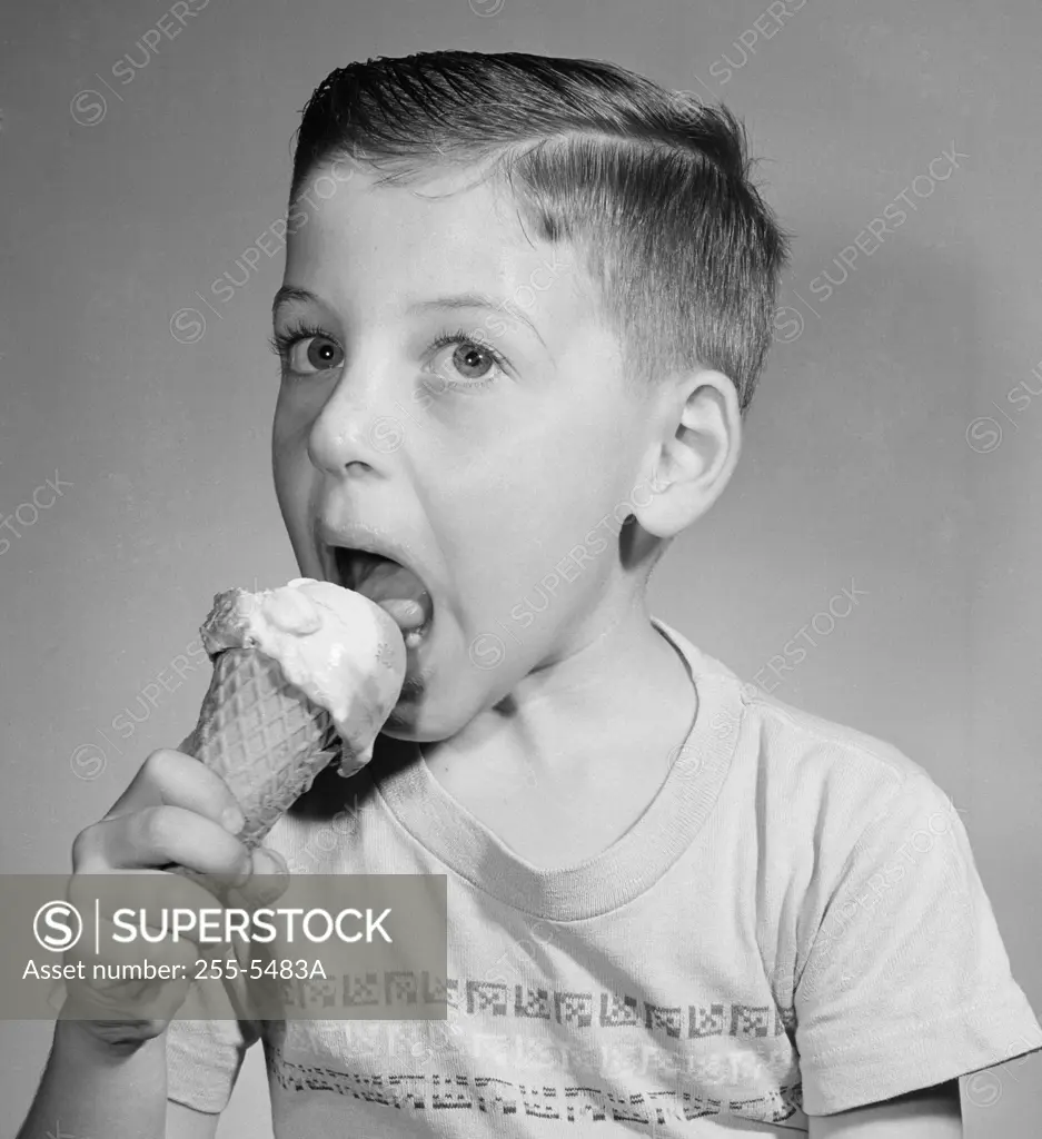 Portrait of boy eating icecream,  studio shot