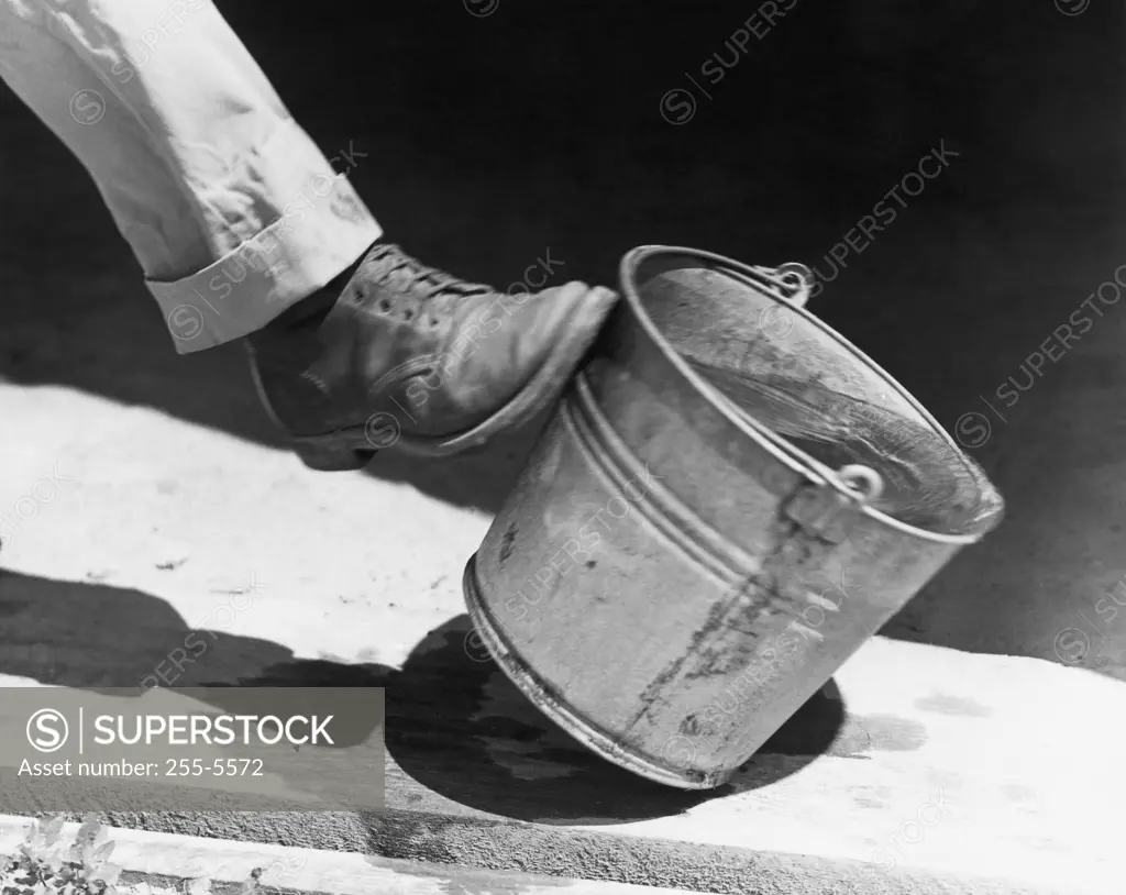 Person's leg kicking a bucket of water