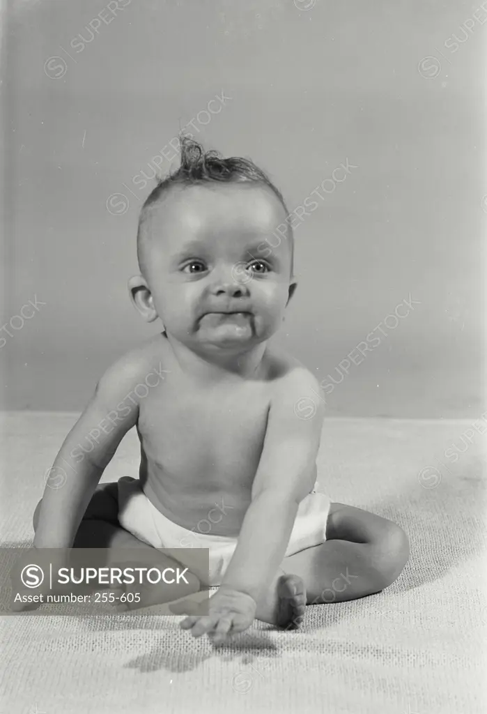 Vintage Photograph. Baby boy sitting on blanket with arms in front